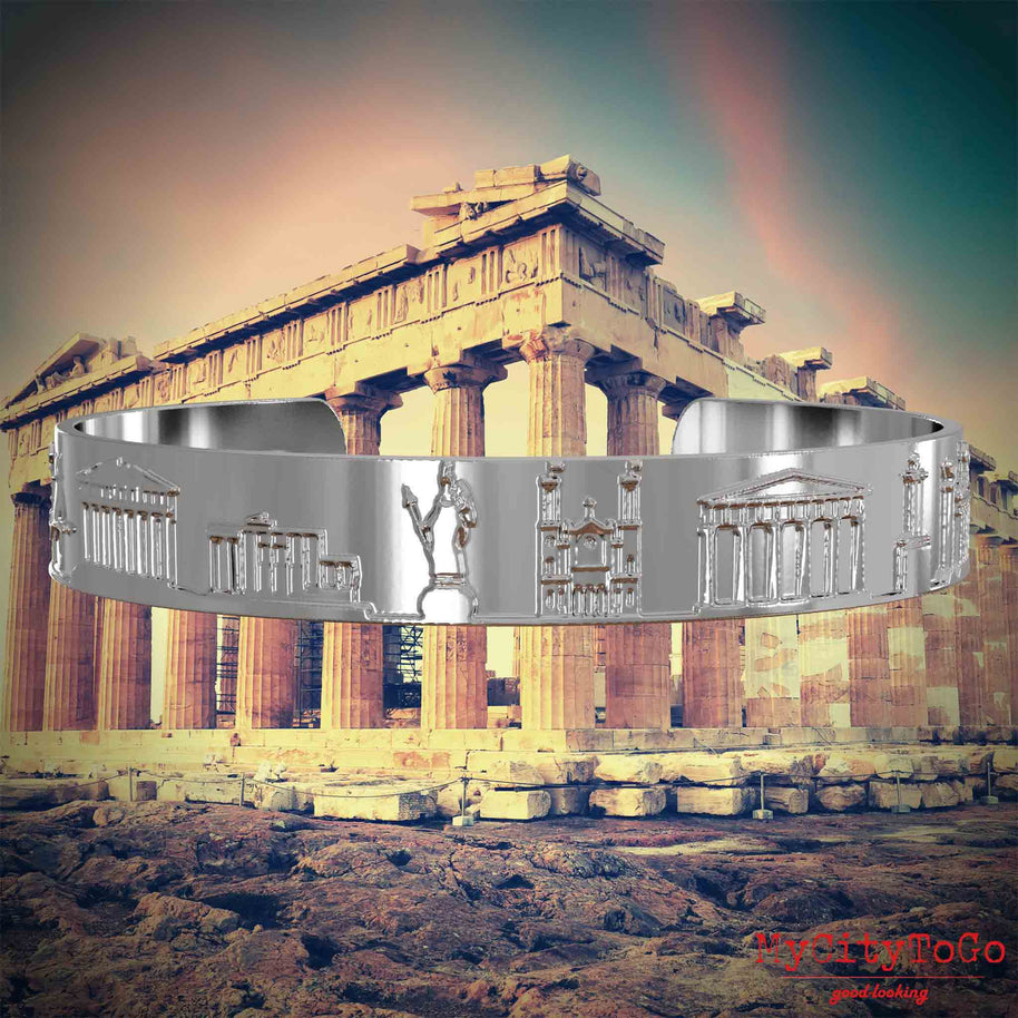 Versilberter Armreif mit Reliefs bekannter Sehenswürdigkeiten der Stadt Athen. Den Hintergrund bildet eine Ansicht der Stadt Athen.