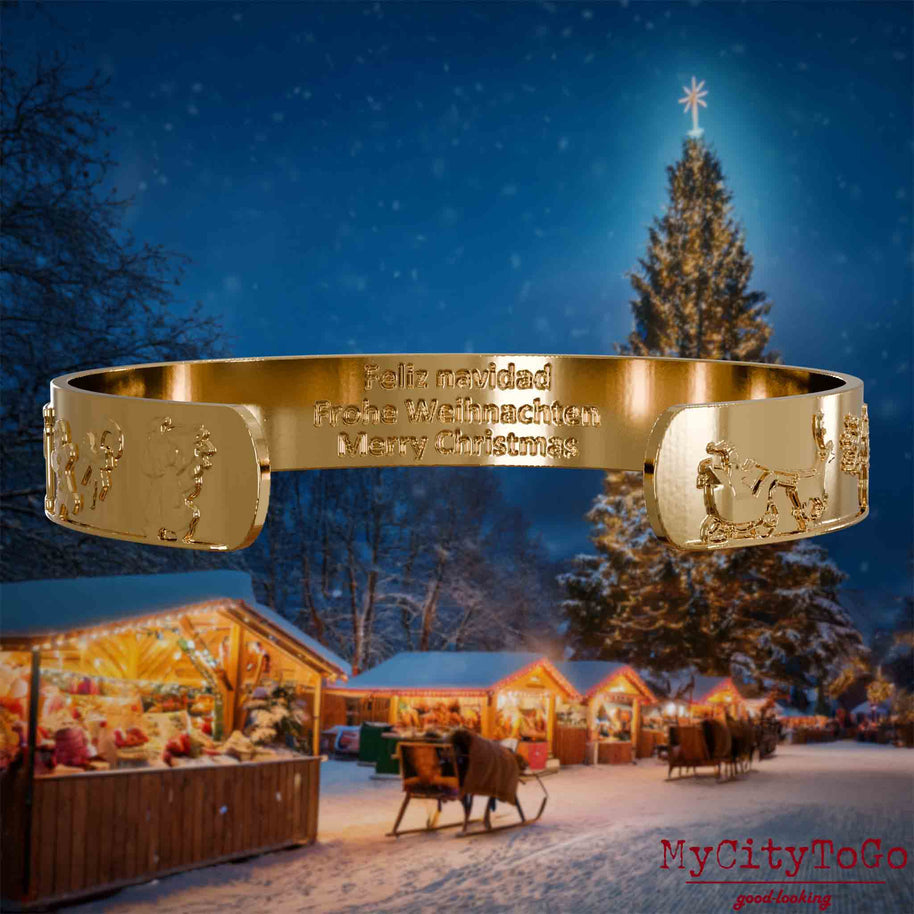 Innenseite eines vergoldeten Armreifs mit Reliefs weihnachtlicher Motive und der mehrsprachigen Gravur Frohe Weihnachten. Den Hintergrund bildet ein naechtliches Weihnachtsmotiv.