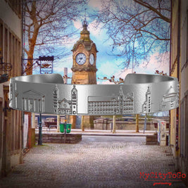 Armreif aus Edelstahl mit Reliefs bekannter Sehenswürdigkeiten der Stadt Duesseldorf. Den Hintergrund bildet eine Ansicht der Stadt Duesseldorf.