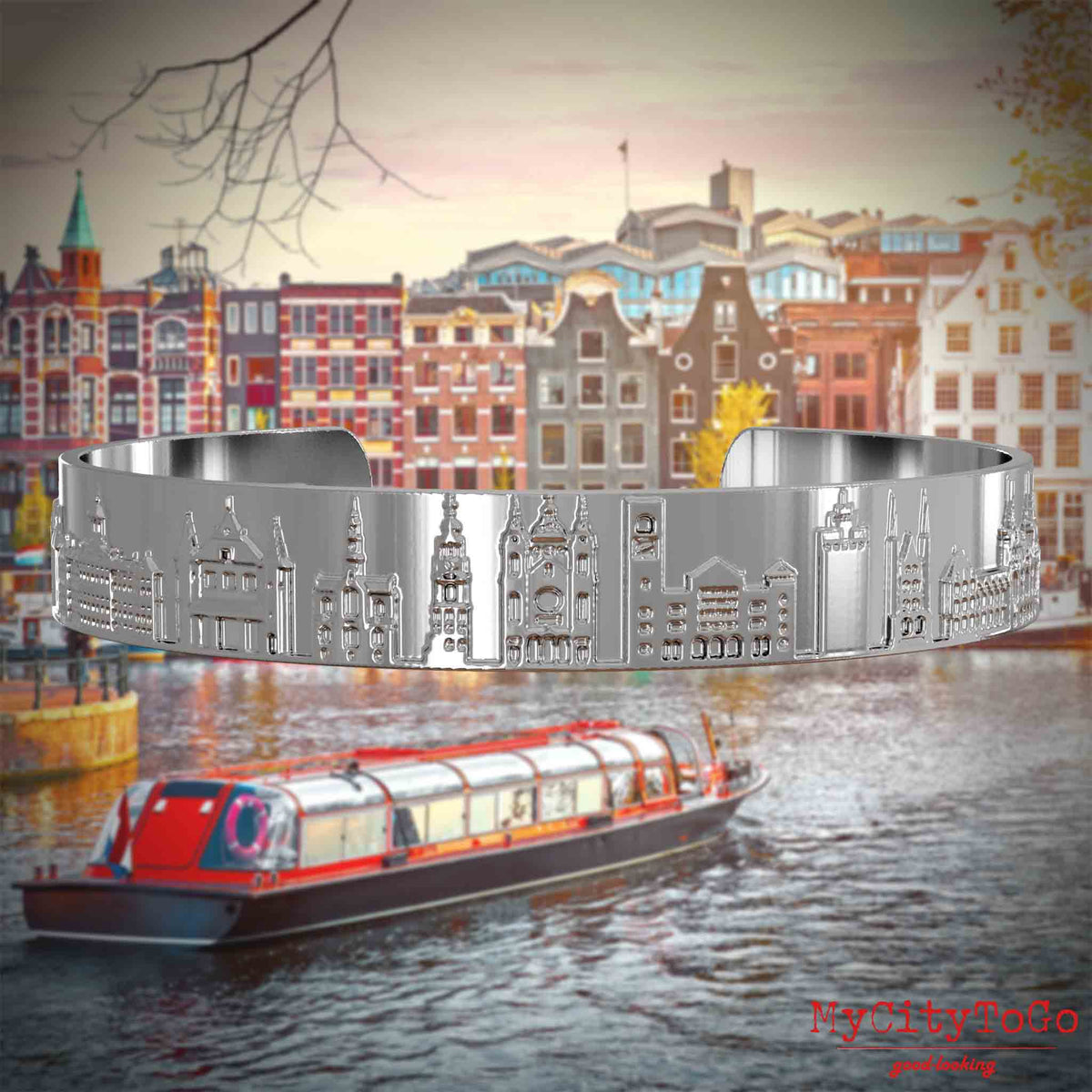 Versilberter Armreif mit Reliefs bekannter Sehenswürdigkeiten der Stadt Amsterdam. Den Hintergrund bildet eine Ansicht der Stadt Amsterdam.