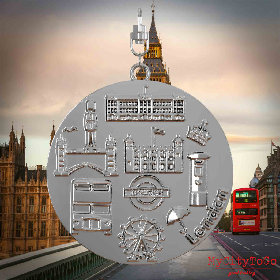 Halskette mit Drehwirbel und Vorderseite eines silbernen Schmuckanhängers, auf dem Reliefs bekannter Sehenswürdigkeiten der Stadt London abgebildet sind. Den Hintergrund bildet eine Ansicht der Stadt London.
