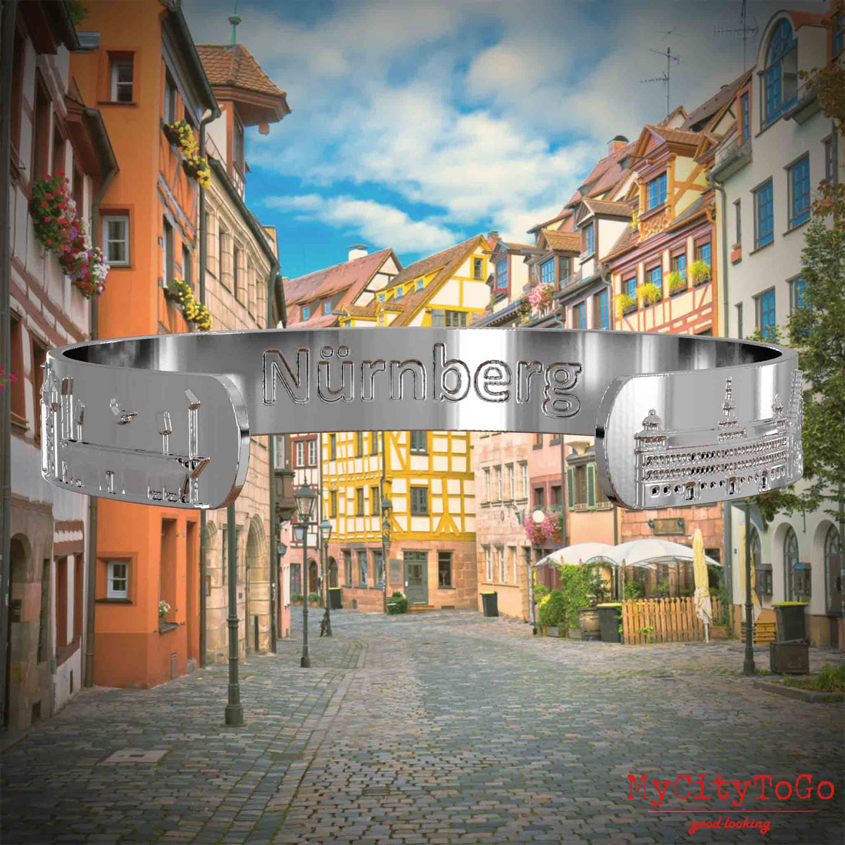 Innenseite eines silbernen Armreifs mit Reliefs bekannter Sehenswürdigkeiten der Stadt Nürnberg und einenr Gravur des Stadtnamens. Den Hintergrund bildet eine Ansicht der Stadt  Nuernberg.