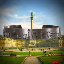 Armreif aus Titan mit Reliefs bekannter Sehenswürdigkeiten der Stadt Stuttgart. Den Hintergrund bildet eine Ansicht der Stadt Stuttgart.