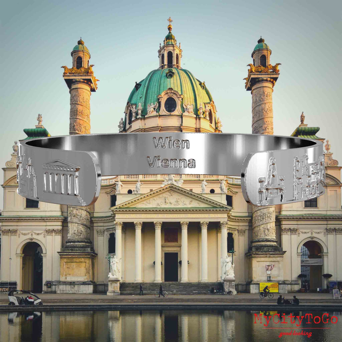 Innenseite eines silbernen Armreifs mit Reliefs bekannter Sehenswürdigkeiten der Stadt Wien und einer Gravur des Stadtnamens . Den Hintergrund bildet eine Ansicht der Stadt Wien.