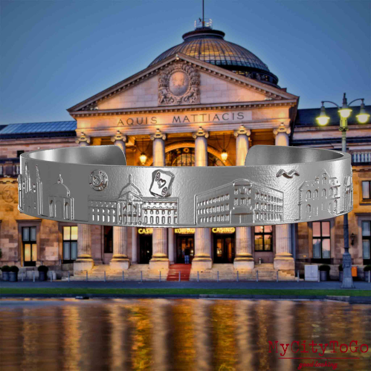 Armreif aus Edelstahl mit Reliefs bekannter Sehenswürdigkeiten der Stadt Wiesbaden. Den Hintergrund bildet eine Ansicht der Stadt Wiesbaden.