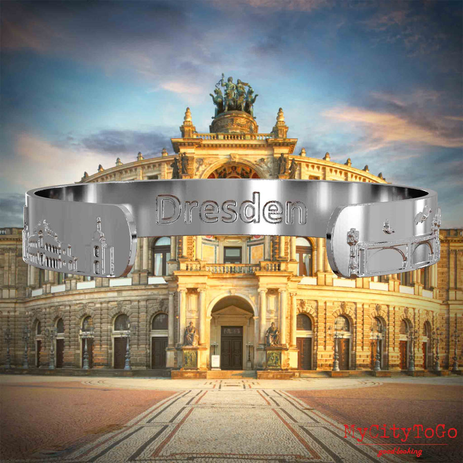 Innenseite eines versilberten Armreifs mit Reliefs bekannter Sehenswürdigkeiten der Stadt Dresden und einer Gravur des Stadtnamens. Den Hintergrund bildet eine Ansicht der Stadt Dresden.