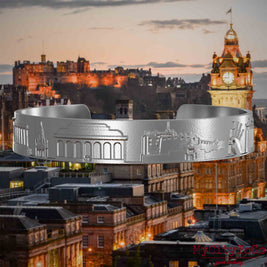 Armreif aus Edelstahl mit Reliefs bekannter Sehenswürdigkeiten der Stadt Edinburgh. Den Hintergrund bildet eine Ansicht der Stadt Edinburgh.