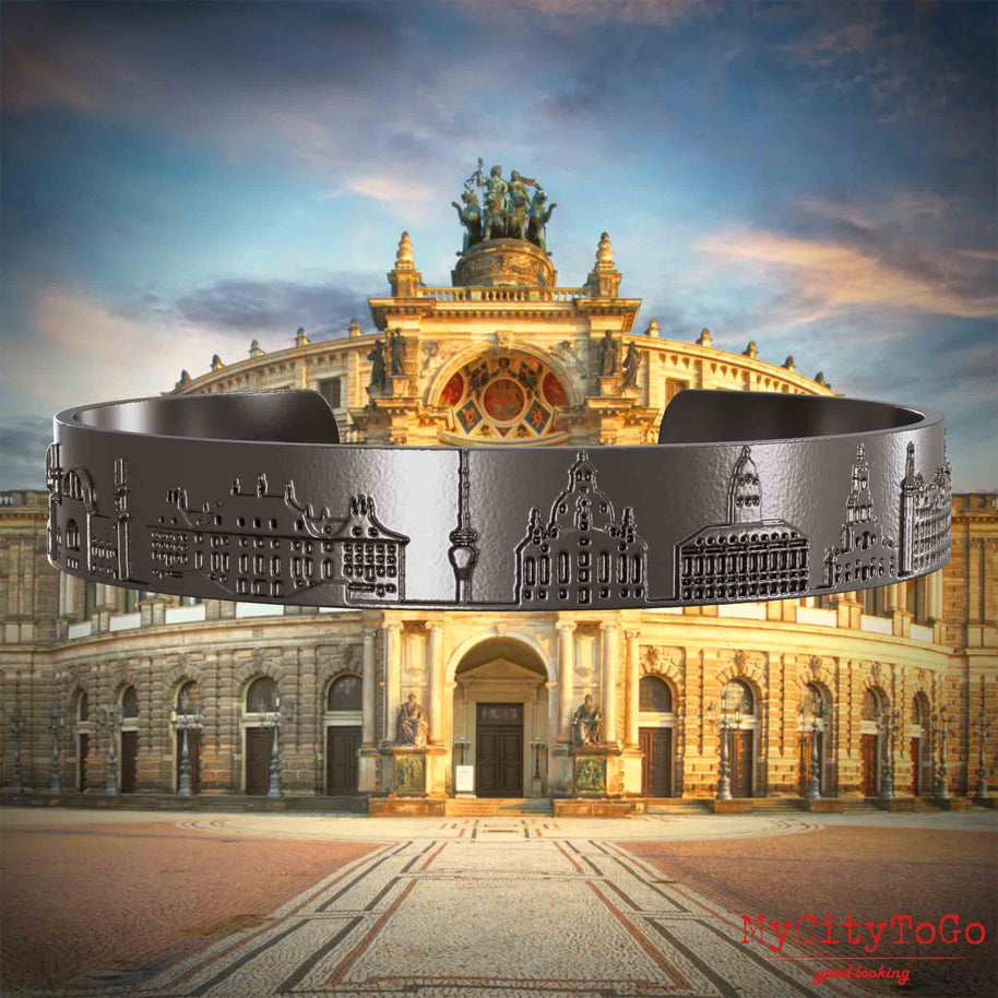 Armreif aus Titan mit Reliefs bekannter Sehenswürdigkeiten der Stadt Dresden. Den Hintergrund bildet eine Ansicht der Stadt Dresden.