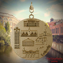 Halskette mit Drehwirbel und Rückseite eines Schmuckanhängers aus vergoldetem Edelstahl, auf dem Reliefs bekannter Sehenswürdigkeiten der Stadt Leipzig abgebildet sind. Den Hintergrund bildet eine Ansicht der Stadt Leipzig.