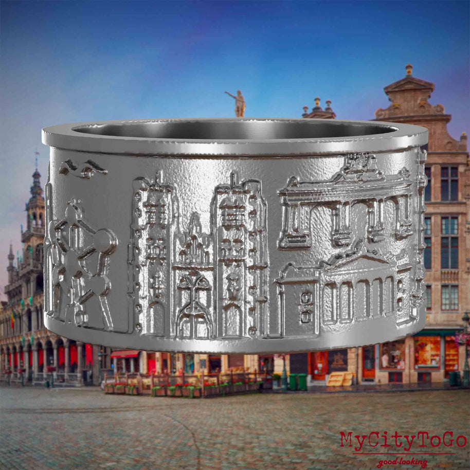 Ring aus Edelstahl mit Reliefs bekannter Sehenswürdigkeiten der Stadt Bruessel. Den Hintergrund bildet eine Ansicht der Stadt Bruessel.