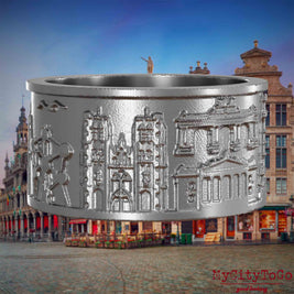 Ring aus Edelstahl mit Reliefs bekannter Sehenswürdigkeiten der Stadt Bruessel. Den Hintergrund bildet eine Ansicht der Stadt Bruessel.