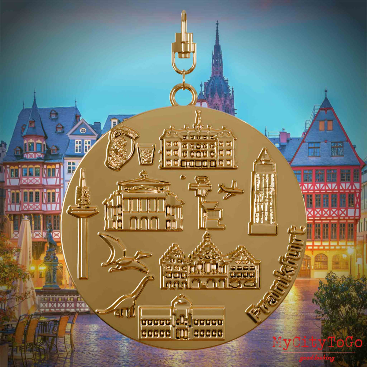 Halskette mit Drehwirbel und Rückseite eines vergoldeten Schmuckanhängers, auf dem Reliefs bekannter Sehenswürdigkeiten der Stadt Frankfurt abgebildet sind. Den Hintergrund bildet eine Ansicht der Stadt Frankfurt.