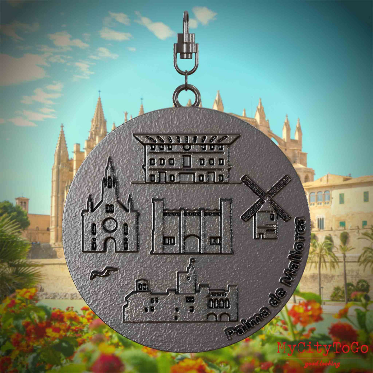 Halskette mit Drehwirbel und Vorderseite eines Schmuckanhängers aus Titan, auf dem Reliefs bekannter Sehenswürdigkeiten der Stadt Palma de Mallorca abgebildet sind. Den Hintergrund bildet eine Ansicht der Stadt Palma de Mallorca.
