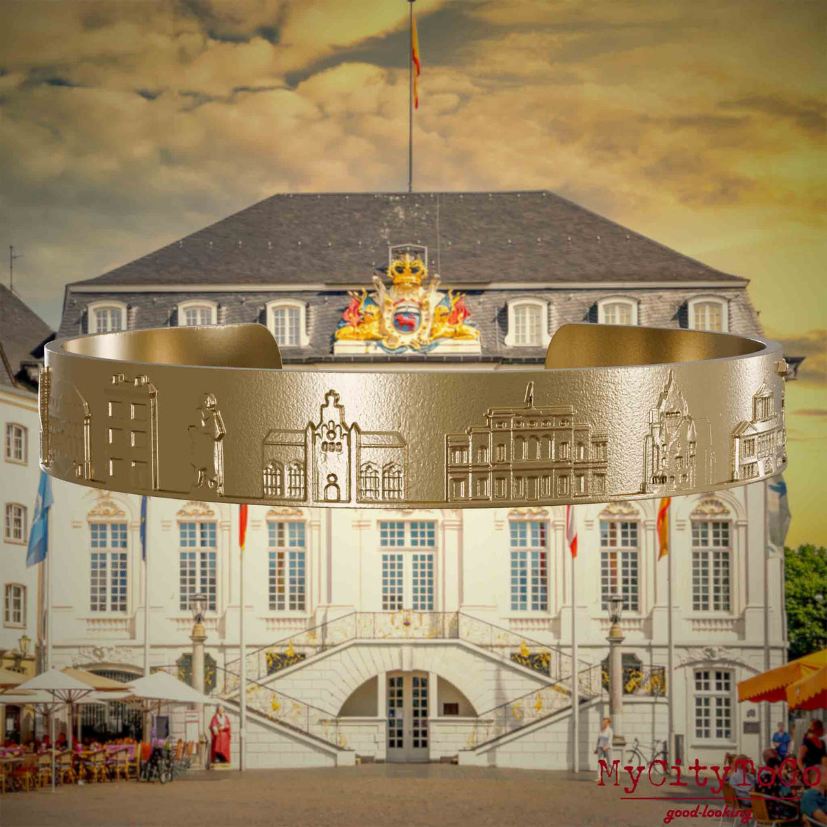Armreif aus vergoldetem Edelstahl mit Reliefs bekannter Sehenswürdigkeiten der Stadt Bonn. Den Hintergrund bildet eine Ansicht der Stadt Bonn.