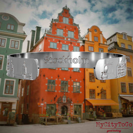 Innenseite eines silbernen Armreifs mit Reliefs bekannter Sehenswürdigkeiten der Stadt Stockholm und einer Gravur des Stadtnamens. Den Hintergrund bildet eine Ansicht der Stadt Stockholm.
