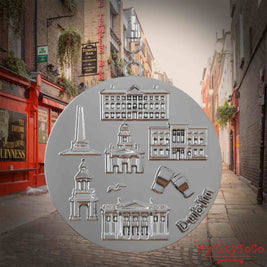 Halskette mit Drehwirbel und Vorderseite eines silbernen Schmuckanhängers, auf dem Reliefs bekannter Sehenswürdigkeiten der Stadt Dublin abgebildet sind. Den Hintergrund bildet eine Ansicht der Stadt Dublin.
