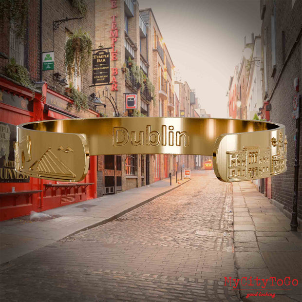 Innenseite eines vergoldeten Armreifs mit Reliefs bekannter Sehenswürdigkeiten der  Stadt Dublin und einer Gravur des Stadtnamens. Den Hintergrund bildet eine Ansicht der Stadt Dublin.