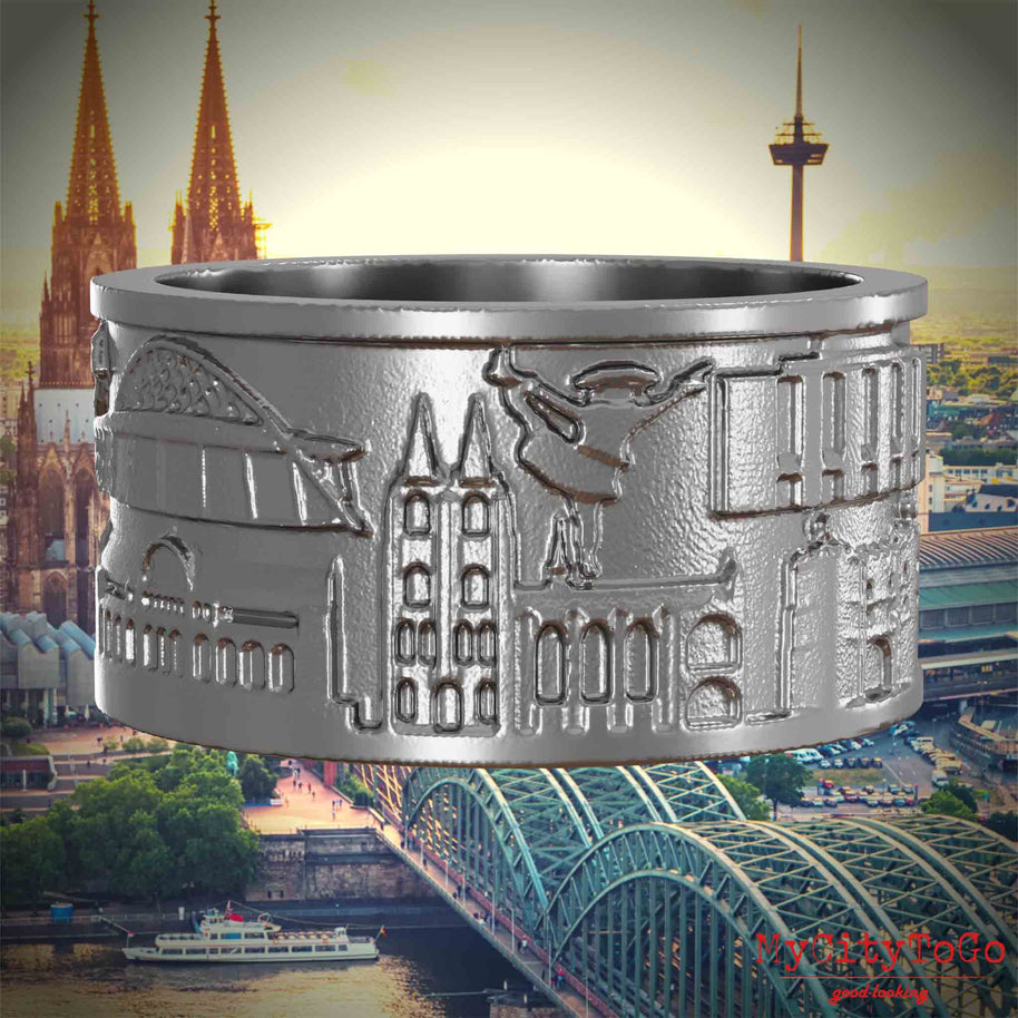 Ring aus Edelstahl mit Reliefs bekannter Sehenswürdigkeiten der Stadt Koeln. Den Hintergrund bildet eine Ansicht der Stadt Koeln.