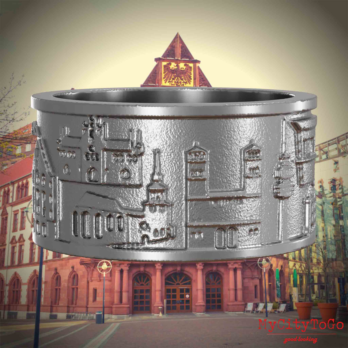 Ring aus Edelstahl mit Reliefs bekannter Sehenswürdigkeiten der Stadt Dortmund. Den Hintergrund bildet eine Ansicht der Stadt Dortmund.