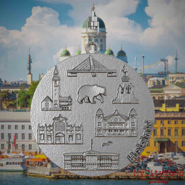 Halskette mit Drehwirbel und Rückseite eines Schmuckanhängers aus Edelstahl, auf dem Reliefs bekannter Sehenswürdigkeiten der Stadt Helsinki abgebildet sind. Den Hintergrund bildet eine Ansicht der Stadt Helsinki.

