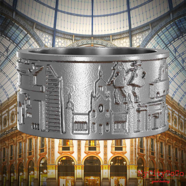 Ring aus Edelstahl mit Reliefs bekannter Sehenswürdigkeiten der Stadt Mailand. Den Hintergrund bildet eine Ansicht der Stadt Mailand.