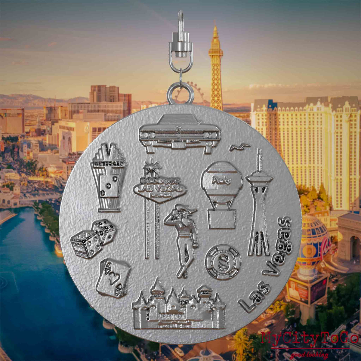 Halskette mit Drehwirbel und Rückseite eines Schmuckanhängers aus Edelstahl, auf dem Reliefs bekannter Sehenswürdigkeiten der Stadt Las Vegas abgebildet sind. Den Hintergrund bildet eine Ansicht der Stadt Las Vegas.