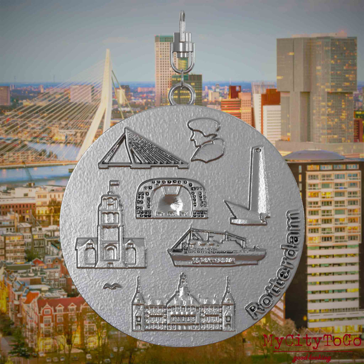 Halskette mit Drehwirbel und Rückseite eines Schmuckanhängers aus Edelstahl, auf dem Reliefs bekannter Sehenswürdigkeiten der Stadt Rotterdam abgebildet sind. Den Hintergrund bildet eine Ansicht der Stadt Rotterdam.
