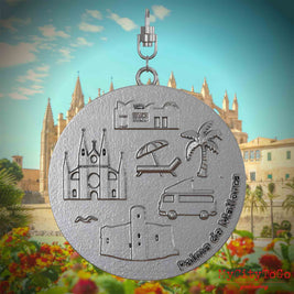 Halskette mit Drehwirbel und Rückseite eines Schmuckanhängers aus Edelstahl, auf dem Reliefs bekannter Sehenswürdigkeiten der Stadt Palma de Mallorca abgebildet sind. Den Hintergrund bildet eine Ansicht der Stadt Palma de Mallorca.
