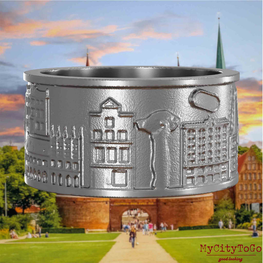 Ring aus Edelstahl mit Reliefs bekannter Sehenswürdigkeiten der Stadt Luebeck. Den Hintergrund bildet eine Ansicht der Stadt Luebeck.