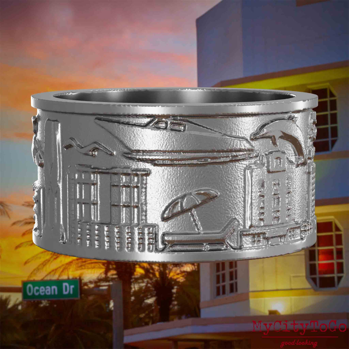 Ring aus Edelstahl mit Reliefs bekannter Sehenswürdigkeiten der Stadt Miami. Den Hintergrund bildet eine Ansicht der Stadt Miami.
