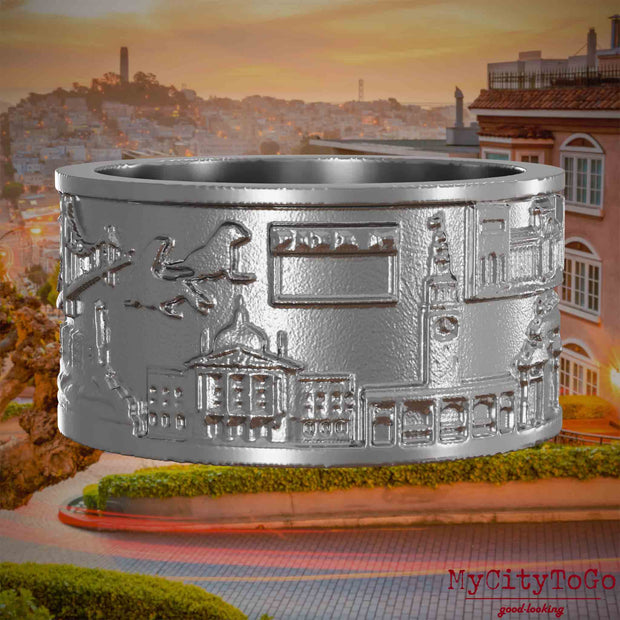 Ring aus Edelstahl mit Reliefs bekannter Sehenswürdigkeiten der Stadt San Francisco. Den Hintergrund bildet eine Ansicht der Stadt San Francisco.