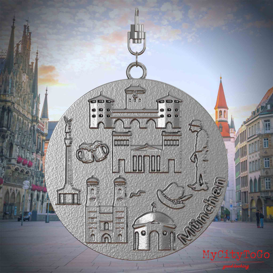 Halskette mit Drehwirbel und Vorderseite eines Schmuckanhängers aus Edelstahl, auf dem Reliefs bekannter Sehenswürdigkeiten der Stadt Muenchen abgebildet sind. Den Hintergrund bildet eine Ansicht der Stadt Muenchen.