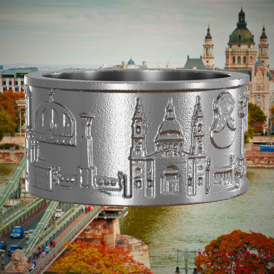 Ring aus Edelstahl mit Reliefs bekannter Sehenswürdigkeiten der Stadt Budapest. Den Hintergrund bildet eine Ansicht der Stadt Budapest.