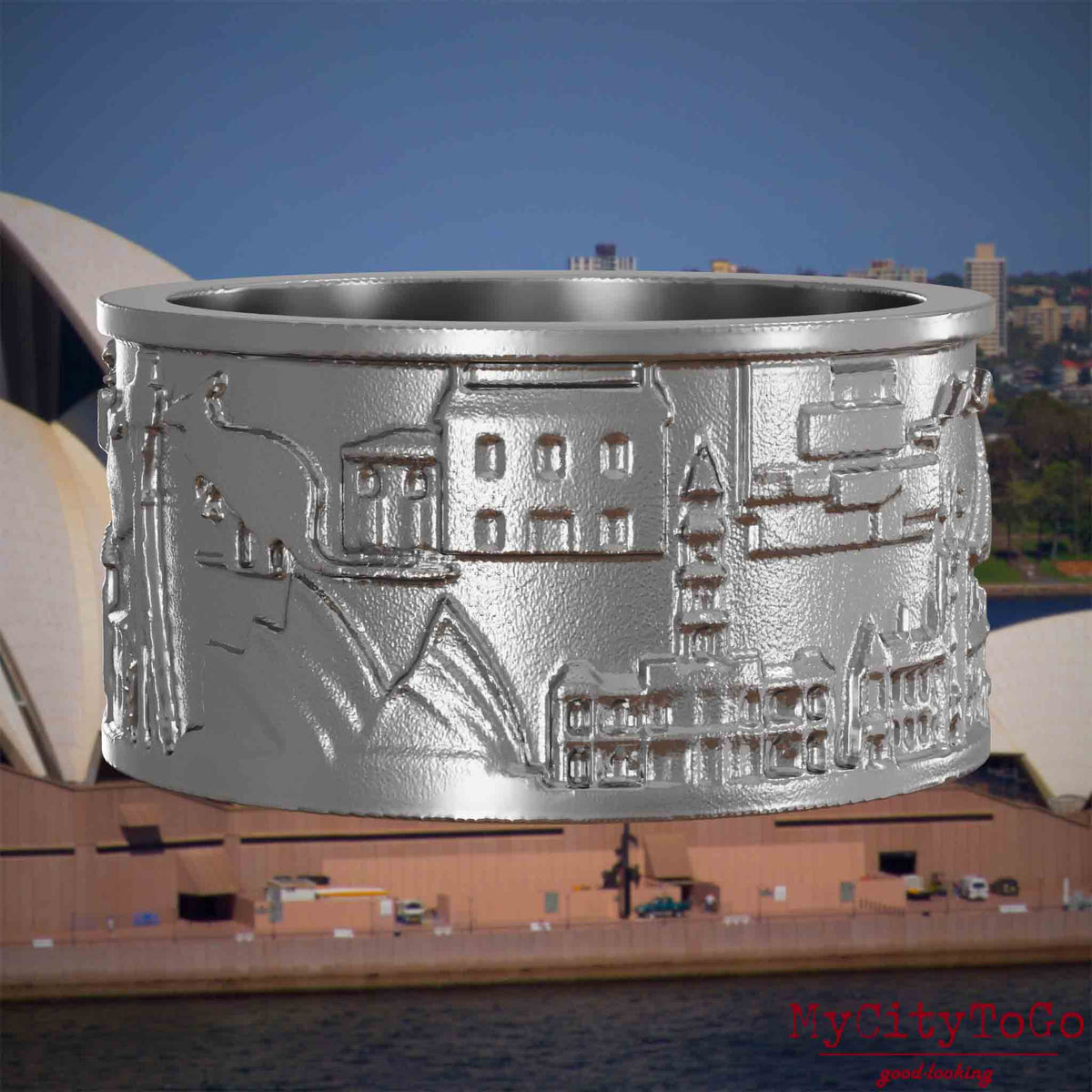 Ring aus Edelstahl mit Reliefs bekannter Sehenswürdigkeiten der Stadt Sydney. Den Hintergrund bildet eine Ansicht der Stadt Sydney.
