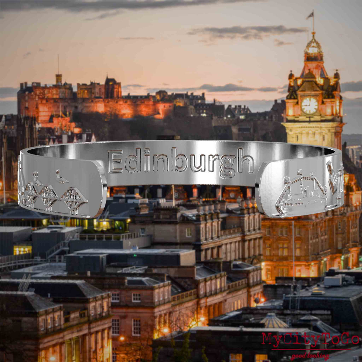 Innenseite eines silbernen Armreifs mit Reliefs bekannter Sehenswürdigkeiten der Stadt Edinburgh und einer Gravur des Stadtnamens. Den Hintergrund bildet eine Ansicht der Stadt Edinburgh.
