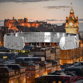 Innenseite eines silbernen Armreifs mit Reliefs bekannter Sehenswürdigkeiten der Stadt Edinburgh und einer Gravur des Stadtnamens. Den Hintergrund bildet eine Ansicht der Stadt Edinburgh.