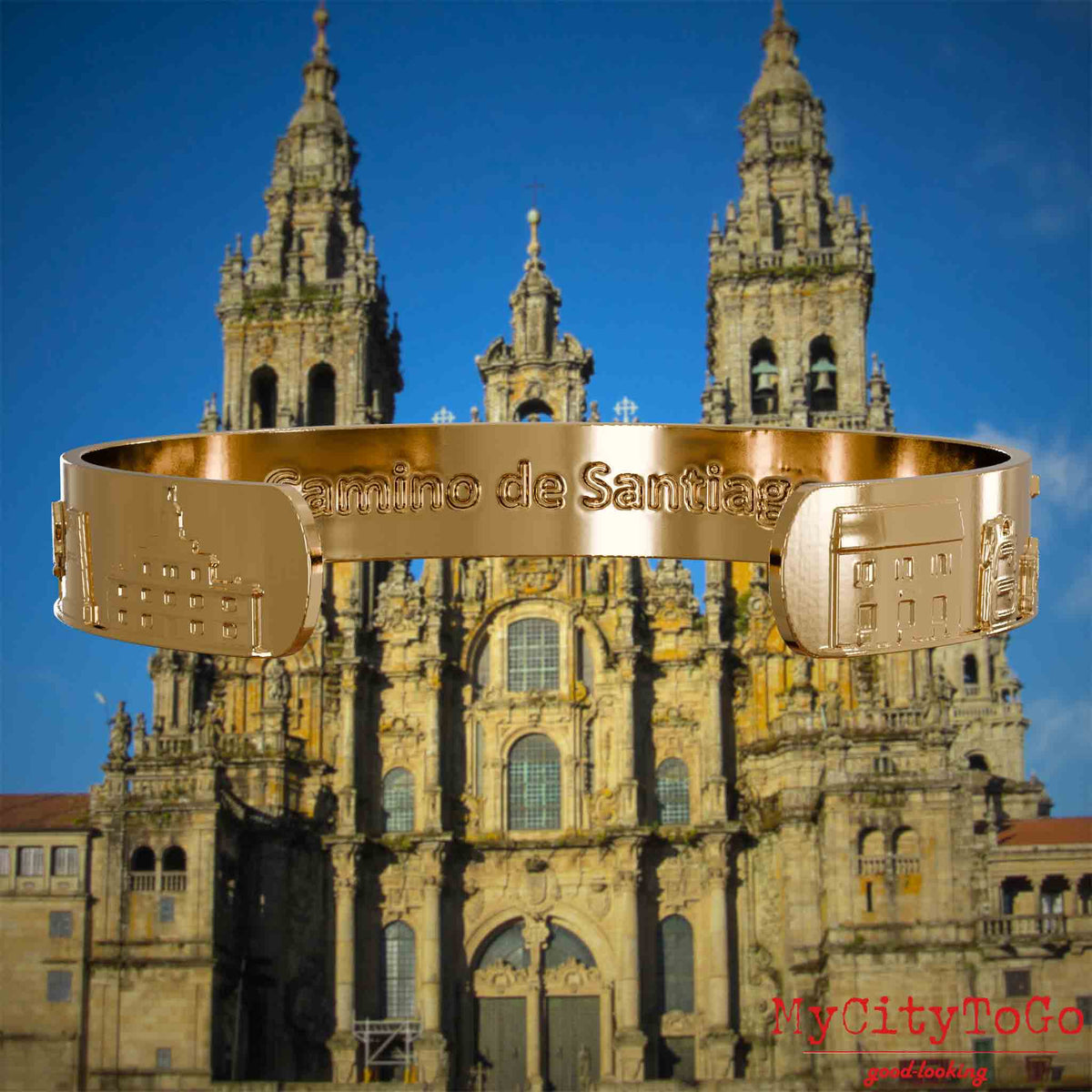 Innenseite eines vergoldeten Armreifs mit Reliefs bekannter Sehenswürdigkeiten und Elemente des Jakobsweges und der Gravur Camino de Santiago. Den Hintergrund bildet die Kathedrale von Santiago de Compostela.