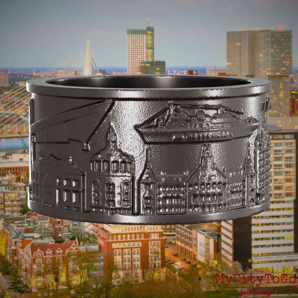 Ring aus Titan mit Reliefs bekannter Sehenswürdigkeiten der Stadt Rotterdam. Den Hintergrund bildet eine Ansicht der Stadt Rotterdam.