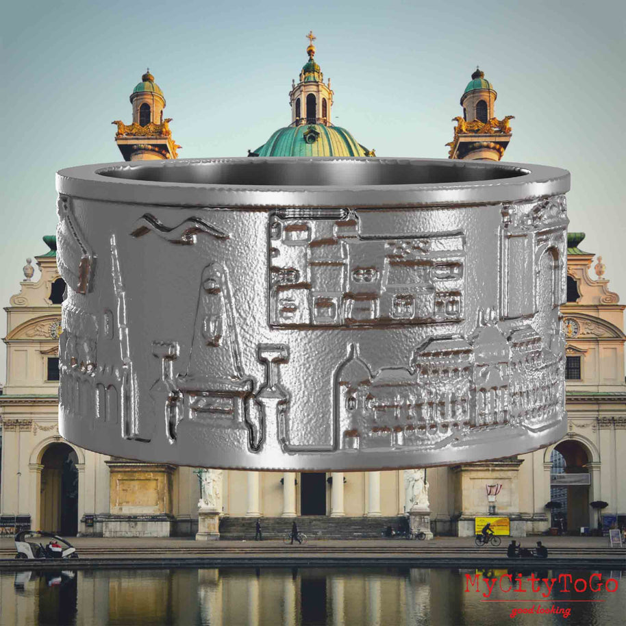 Ring aus Edelstahl mit Reliefs bekannter Sehenswürdigkeiten der Stadt Wien. Den Hintergrund bildet eine Ansicht der Stadt Wien.