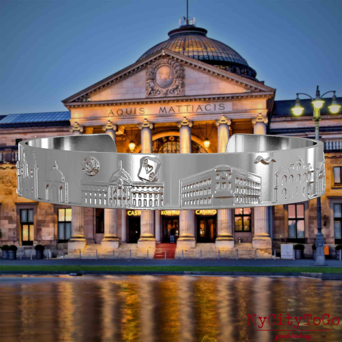 Versilberter Armreif mit Reliefs bekannter Sehenswürdigkeiten der Stadt Wiesbaden. Den Hintergrund bildet eine Ansicht der Stadt Wiesbaden.