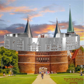 Versilberter Armreif mit Reliefs bekannter Sehenswürdigkeiten der Stadt Luebeck. Den Hintergrund bildet eine Ansicht der Stadt Luebeck.