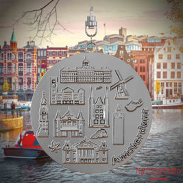 Halskette mit Drehwirbel und Rückseite eines silbernen Schmuckanhängers, auf dem Reliefs bekannter Sehenswürdigkeiten der Stadt Amsterdam abgebildet sind. Den Hintergrund bildet eine Ansicht der Stadt Amsterdam.
