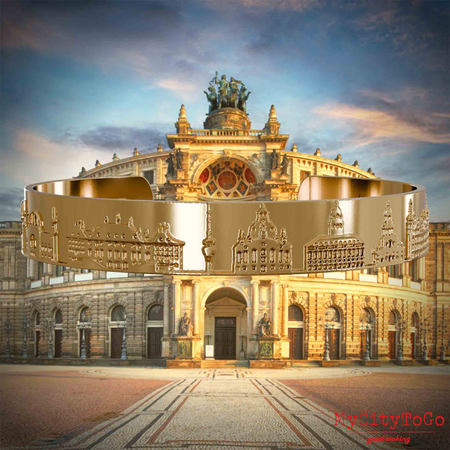 Vergoldeter Armreif mit Reliefs bekannter Sehenswürdigkeiten der Stadt Dresden. Den Hintergrund bildet eine Ansicht der Stadt Dresden.