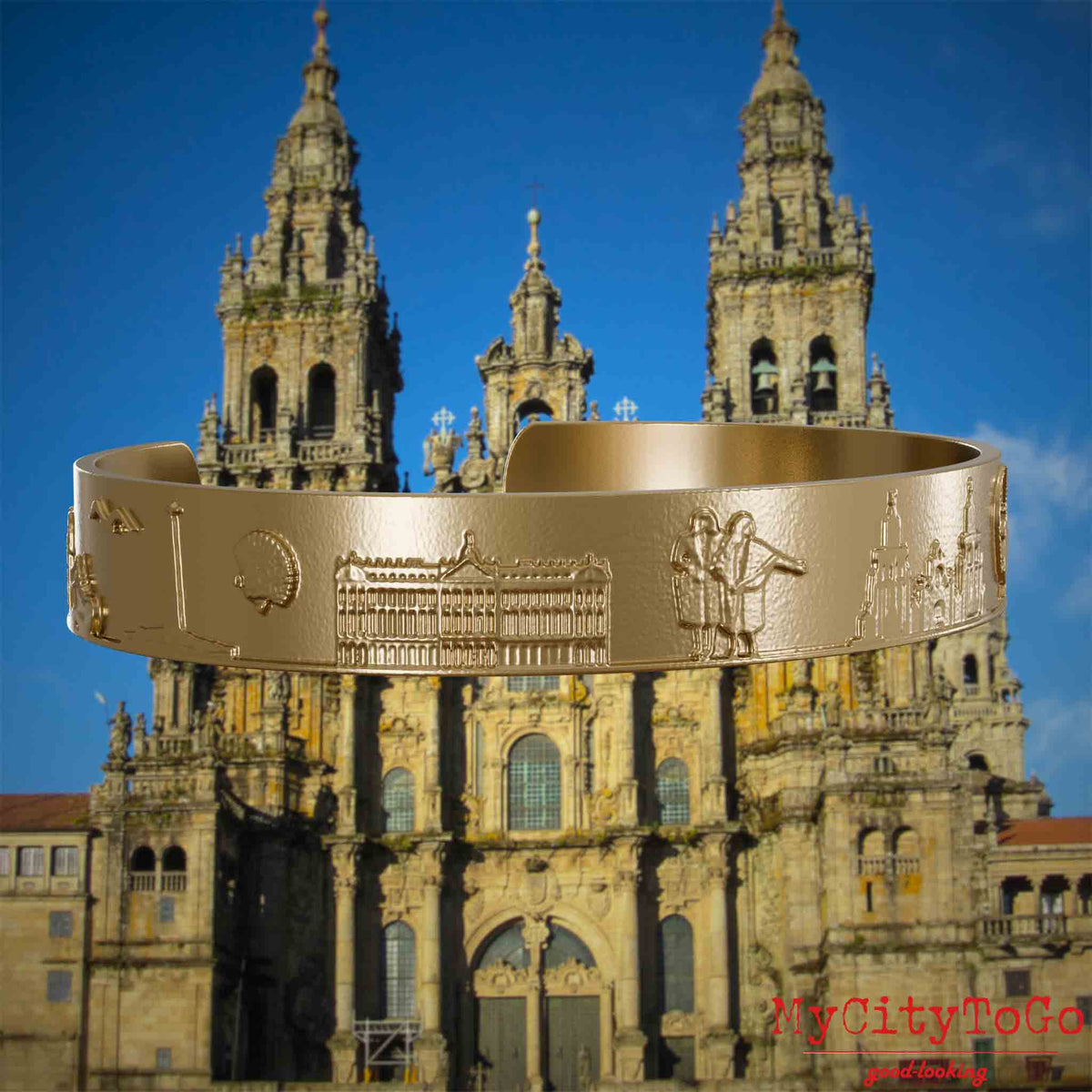 Armreif aus vergoldetem Edelstahl mit Reliefs bekannter Sehenswürdigkeiten und Elemente des Jakobsweges. Den Hintergrund bildet die Kathedrale von Santiago de Compostela.