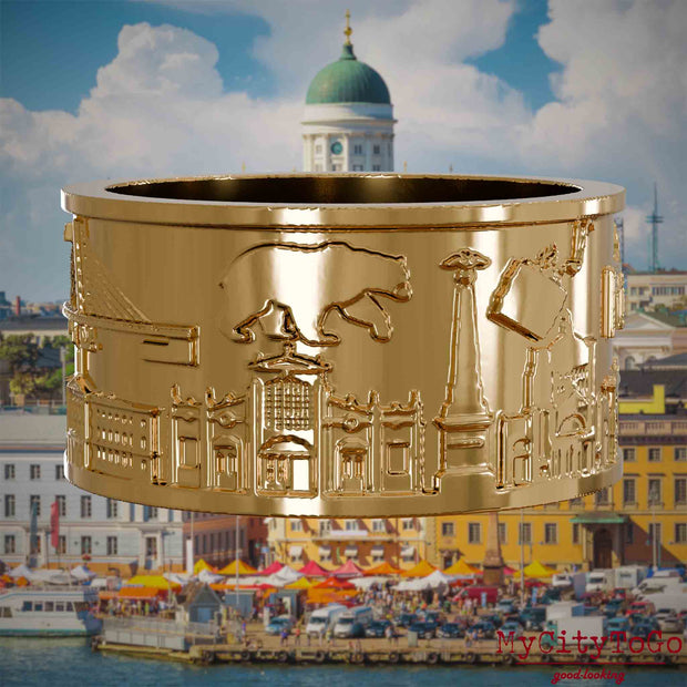 Vergoldeter Ring mit Reliefs bekannter Sehenswürdigkeiten der Stadt Helsinki. Den Hintergrund bildet eine Ansicht der Stadt Helsinki.