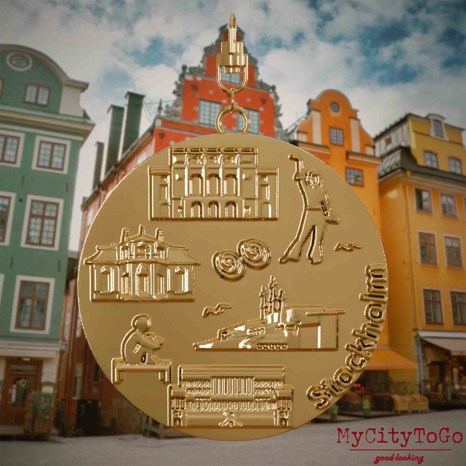 Halskette mit Drehwirbel und Vorderseite eines vergoldeten Schmuckanhängers, auf dem Reliefs bekannter Sehenswürdigkeiten der Stadt Stockholm abgebildet sind. Den Hintergrund bildet eine Ansicht der Stadt Stockholm.
