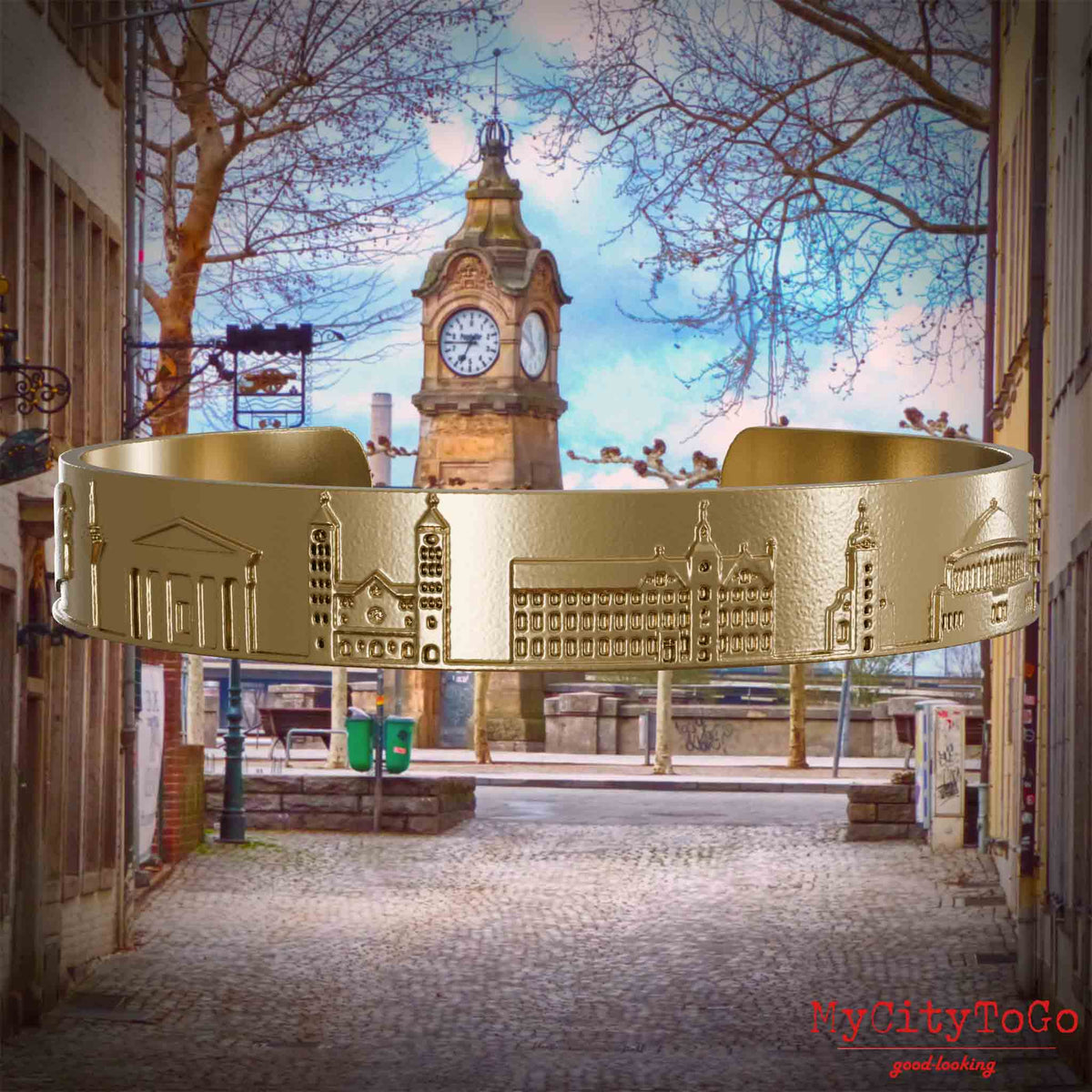 Armreif aus vergoldetem Edelstahl mit Reliefs bekannter Sehenswürdigkeiten der Stadt Duesseldorf. Den Hintergrund bildet eine Ansicht der Stadt Duesseldorf.