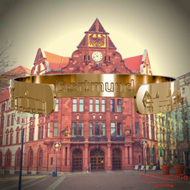 Innenseite eines vergoldeten Armreifs mit Reliefs bekannter Sehenswürdigkeiten der Stadt Dortmund und einer Gravur des Stadtnamens. Den Hintergrund bildet eine Ansicht der Stadt Dortmund.