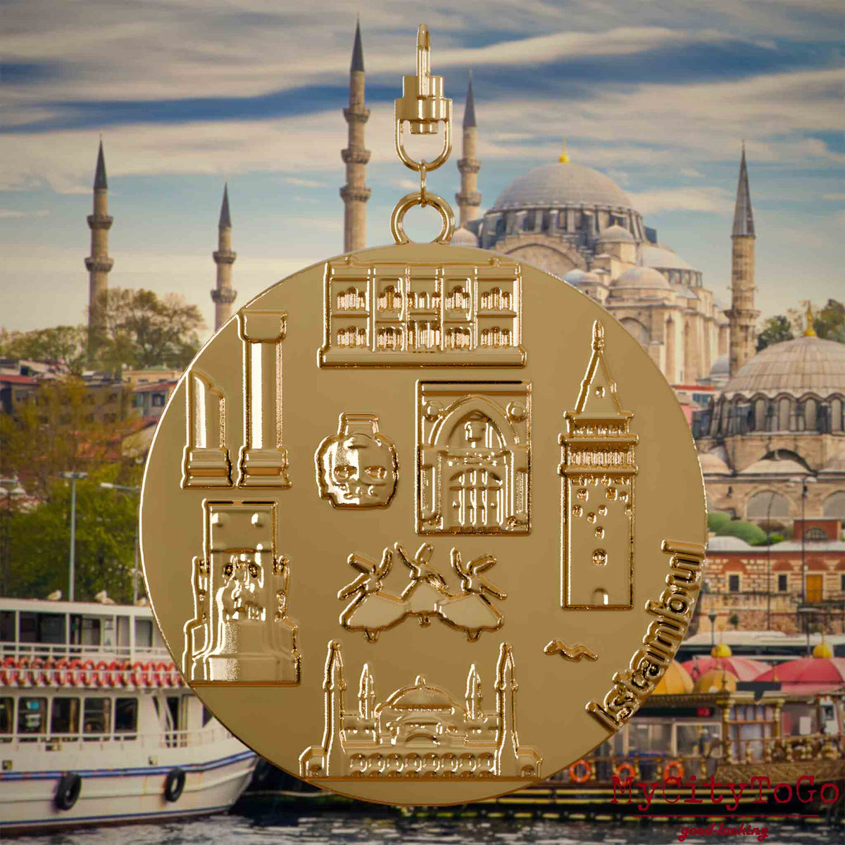Halskette mit Drehwirbel und Rückseite eines vergoldeten Schmuckanhängers, auf dem Reliefs bekannter Sehenswürdigkeiten der Stadt Istanbul abgebildet sind. Den Hintergrund bildet eine Ansicht der Stadt Istanbul.
