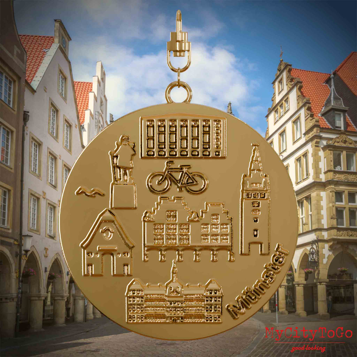 Halskette mit Drehwirbel und Rückseite eines vergoldeten Schmuckanhängers, auf dem Reliefs bekannter Sehenswürdigkeiten der Stadt Muenster abgebildet sind. Den Hintergrund bildet eine Ansicht der Stadt Muenster.